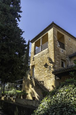 Dayanıklı, heybetli bir taş binanın büyük girişine çıkan bir dizi merdiveni vardır ve gür ağaçlar ve canlı çalılarla güzel bir şekilde çevrilidir.