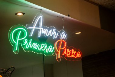 Primavera Pizza yazan parlak neon bir tabela duvarda güzel asılı, kolayca göze çarpıyor ve dikkat çekiyor.