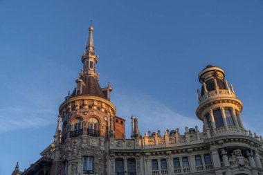 Tepesinde belirgin bir kule bulunan büyük ve etkileyici bir bina, majestelerini yükselten açık mavi bir gökyüzüne karşı kurulmuş.