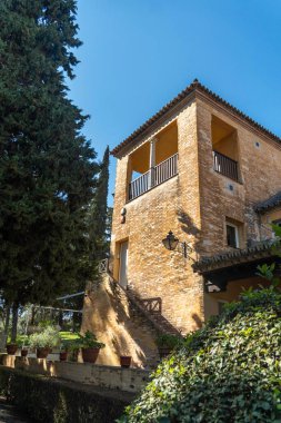 Dayanıklı, heybetli bir taş binanın büyük girişine çıkan bir dizi merdiveni vardır ve gür ağaçlar ve canlı çalılarla güzel bir şekilde çevrilidir.