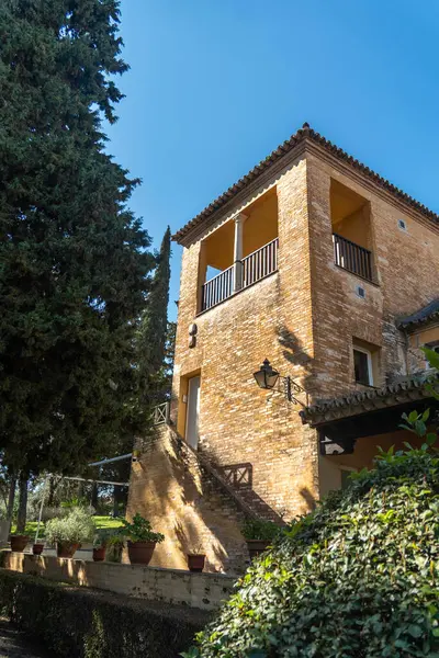 Dayanıklı, heybetli bir taş binanın büyük girişine çıkan bir dizi merdiveni vardır ve gür ağaçlar ve canlı çalılarla güzel bir şekilde çevrilidir.