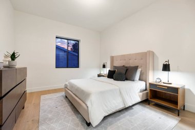 Konforlu bir yatak odası, şık bir komodin, geniş bir şifonyer ve doğal ışık katan güzel bir pencere.