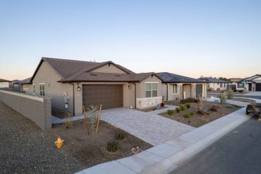 Sessiz bir yerleşim bölgesinde, önünde belirgin bir şekilde park etmiş bir arabanın bulunduğu güzel bir evi gösteren bir hava manzarası.