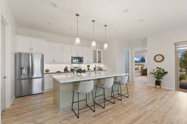 Saf beyaz dolaplarla süslenmiş zarif bir mutfak modern paslanmaz çelik aletler ve ek işlevsellik için geniş bir merkez ada.