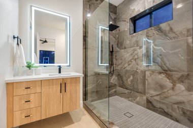 Yürüyen bir duş, şık bir lavabo ve işlevsellik ve estetik için güzel tasarlanmış bir ayna içeren geniş bir banyo.