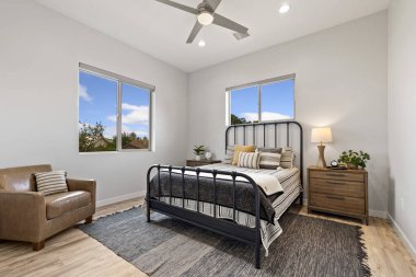 Bu rahat bir yatak odası, şık bir sandalye, uygun bir komodin ve ilave rahatlık için bir tavan vantilatörü.