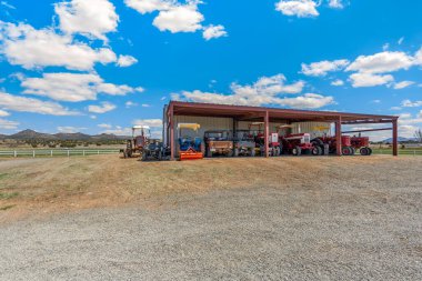 Şu anda büyük bir binanın önüne park edilmiş uzun bir traktör sırası bölgede çarpıcı bir tarımsal mekanizma görüntüsü yaratıyor.