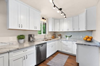 Bu güzel mutfak zarif beyaz dolaplar ve modern paslanmaz çelik aletler içeriyor. Yemek pişirmek için şık ve işlevsel bir alan yaratıyor.