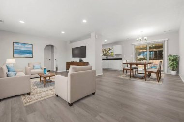 Rahat bir kanepe, şık sandalyeler, zarif bir masa ve eğlence amaçlı modern bir televizyon sunan rahat bir oturma odası.