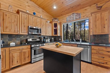 Zarif ahşap dolapları olan, modern paslanmaz çelik aletlerle donatılmış, davetkar bir atmosfer için güzel tasarlanmış bir mutfak.