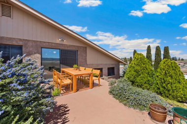 Verandada, etrafındaki dağların çarpıcı manzarasının tadını çıkarmak için mükemmel bir şekilde yerleştirilmiş birkaç sandalyeyle birlikte güzel bir masa var.