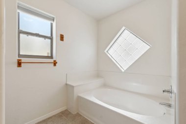 Rahatlatıcı bir küveti ve doğal ışık için uygun bir penceresi olan rahat bir banyo.