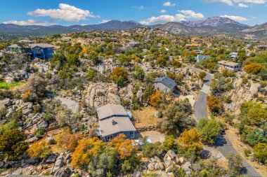 Bu, bereketli ağaçlar ve dağınık kayalarla çevrili manzaralı bir tepenin üzerine tünemiş güzel bir evi gösteren hava manzarası.