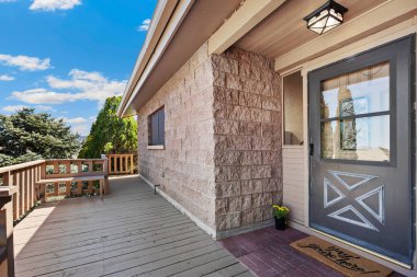 Hoş bir ahşap güverte ve girişte sıcak ve rahat bir siyah kapı olan büyüleyici bir tuğla ev.