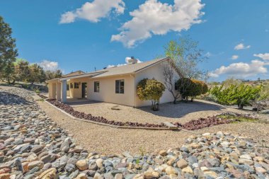 Geniş, büyük bir ev var. Uzun bir garaj yolu var. Etrafı çeşitli ağaçlar ve gür çalılarla çevrili.