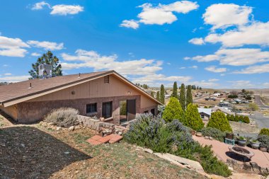 Geniş, büyük bir ev var. Uzun bir garaj yolu var. Etrafı çeşitli ağaçlar ve gür çalılarla çevrili.