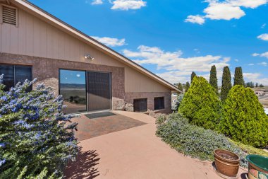 Geniş, büyük bir ev var. Uzun bir garaj yolu var. Etrafı çeşitli ağaçlar ve gür çalılarla çevrili.