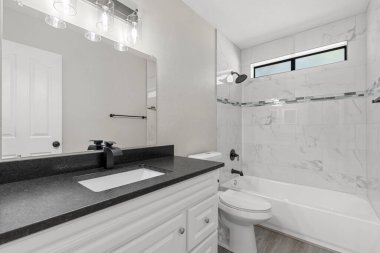 Lavabo, tuvalet, rahat bir küvet ve güzellik rutinleri için şık bir ayna gibi temel özellikleri olan iyi tasarlanmış bir banyo.
