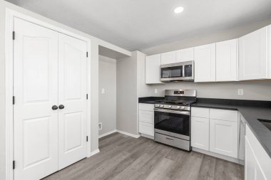 Zarif beyaz dolapları, modern paslanmaz çelik aletleri ve çarpıcı ahşap döşemeleri olan güzel tasarlanmış bir mutfak.