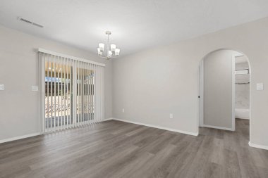 Oturma odası tamamen boş. Güzel ahşap zeminler ve doğal ışık getiren büyük cam kapılar var.