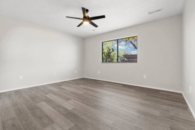 Oturma odası tamamen boş. Güzel ahşap zeminler ve doğal ışık getiren büyük cam kapılar var.