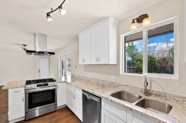 Zarif beyaz dolaplarla donatılmış, paslanmaz çelik aletlerle donatılmış, güzel tasarlanmış bir mutfak.