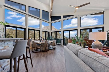 Burası geniş bir oturma odası. İçeriye doğal ışık ve havalandırma için tavan vantilatörü de dahil olmak üzere bir sürü pencere var.