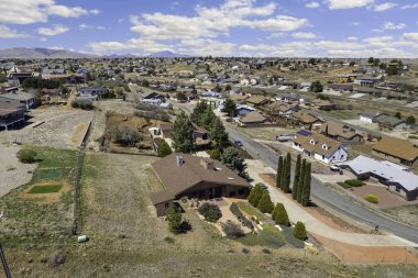 Bu görüntü, benzer evlerle çevrili canlı bir yerleşim yerinin tam ortasında bulunan büyüleyici bir evin havadan görünüşünü gösteriyor.