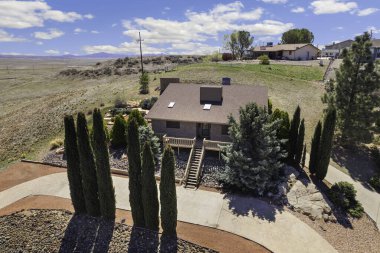 Bu hava manzaralı güzel bir ev, güzel bir şekilde yemyeşil ağaçlarla çevrili ve dolambaçlı bir garaj yolu var.