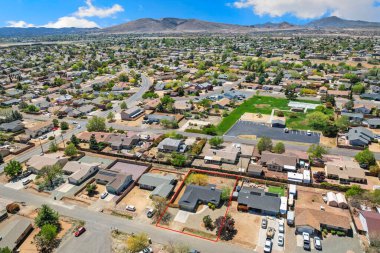 Yüksek bir açıyla, arka planda muazzam bir yükseliş gösteren dağlarla çevrili bir yerleşim bölgesinin görüntüsünü yakalıyor.