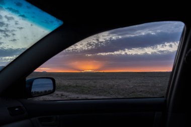 Güzel bir gün batımının nefes kesici görüntüsü. Bir arabanın içinde, gün batımında manzaralı bir yolda giderken rahat bir şekilde.