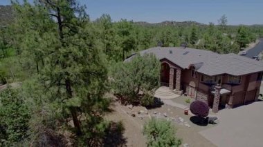 Bu hava görüntülerinde, ağaçlar ve dağ manzaralarıyla çevrili gür bir ormanda doğanın güzelliğini vurgulayan çarpıcı bir ev var.
