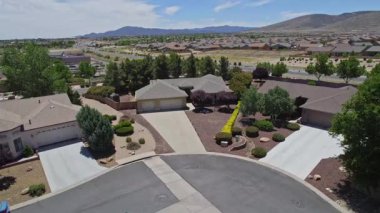 Geniş bir garaj yolu olan güzel bir ev ve önünde zarif bir şekilde duran birkaç ağaç, doğal gölgeler sunuyor ve manzarayı güzelleştiriyor.