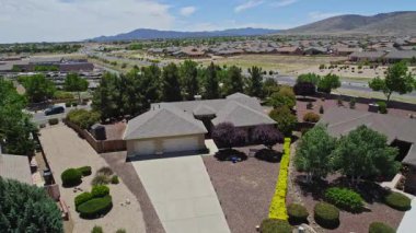 Geniş bir garaj yolu olan güzel bir ev ve önünde zarif bir şekilde duran birkaç ağaç, doğal gölgeler sunuyor ve manzarayı güzelleştiriyor.