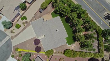 Geniş bir garaj yolu olan güzel bir ev ve önünde zarif bir şekilde duran birkaç ağaç, doğal gölgeler sunuyor ve manzarayı güzelleştiriyor.