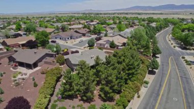 Geniş bir garaj yolu olan güzel bir ev ve önünde zarif bir şekilde duran birkaç ağaç, doğal gölgeler sunuyor ve manzarayı güzelleştiriyor.