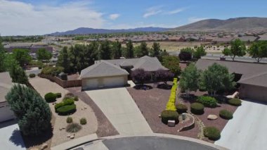 Geniş bir garaj yolu olan güzel bir ev ve önünde zarif bir şekilde duran birkaç ağaç, doğal gölgeler sunuyor ve manzarayı güzelleştiriyor.