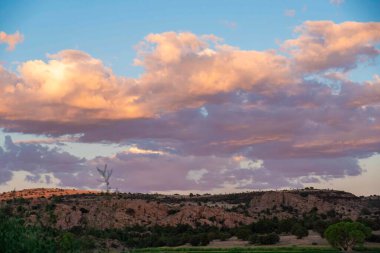 Görkemli bir dağın üzerinde güzel bir günbatımı, bulutların bolluğu ile süslenmiş, berrak bir akşam gökyüzünde zarafetle sürükleniyor, nefes kesici bir manzara yaratıyor.