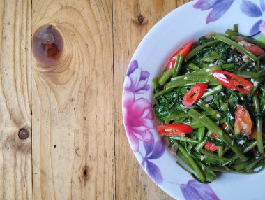 Tumis kangkung ya da karıştırılmış su ıspanağı ahşap masa üzerinde üst açı ve kopyalama alanı, Endonezya yemeği. 