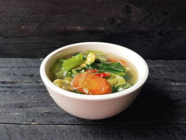 Sebze çorbası beyaz kasede siyah tahta masa arkasında yüksek açılı manzaralı. 