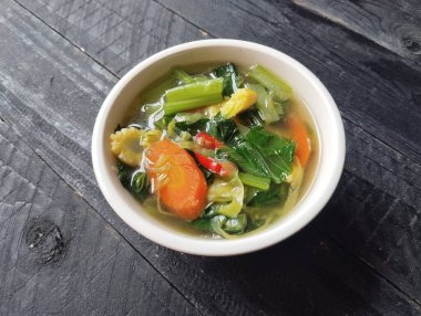 Sebze çorbası beyaz kasede siyah tahta masa arkasında yüksek açılı manzaralı. 