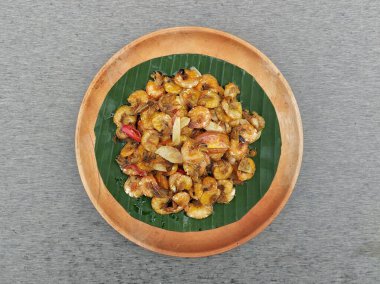 Ahşap tabakta kızartılmış tatlı ve baharatlı karides, gri arka plan, düz yatıyordu.