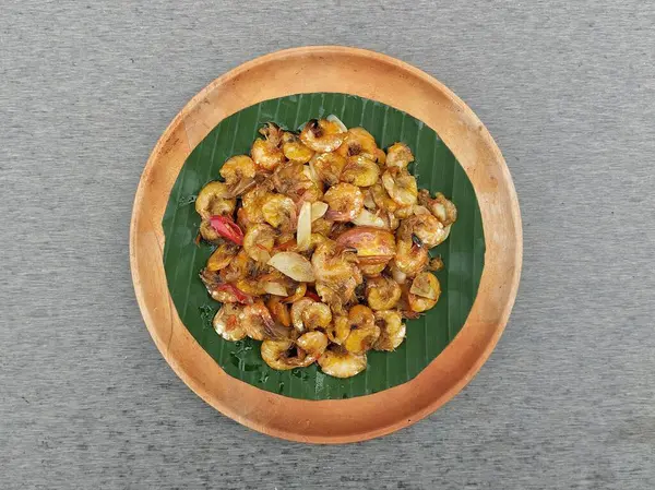 Ahşap tabakta kızartılmış tatlı ve baharatlı karides, gri arka plan, düz yatıyordu.