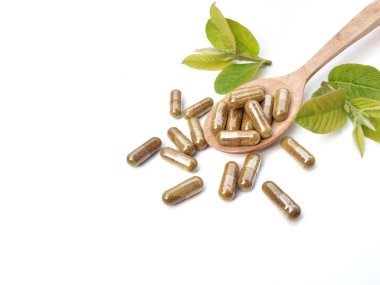 Alternatif tıp bitkisel kapsülleri tahta kaşıkta, beyaz arka planda yeşil yaprak, Top view 