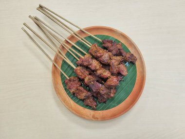 Satay ya da sate, Endonezya baharatlı şiş ve ızgara eti ahşap tabakta sosla servis edilir.