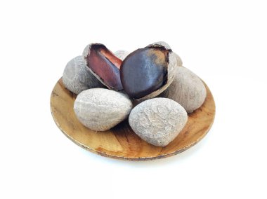 Beyaz arka planda izole edilmiş Pangium fındıkları (pangium edule) ya da tahta tabakta kluwak fındıkları