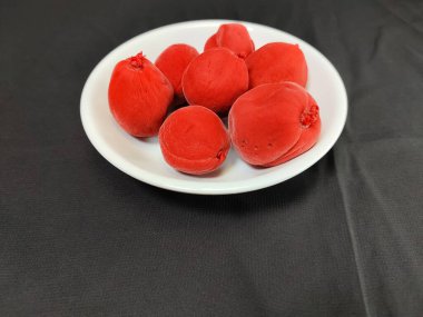 close up of a plate of candied red peaches on a black background clipart