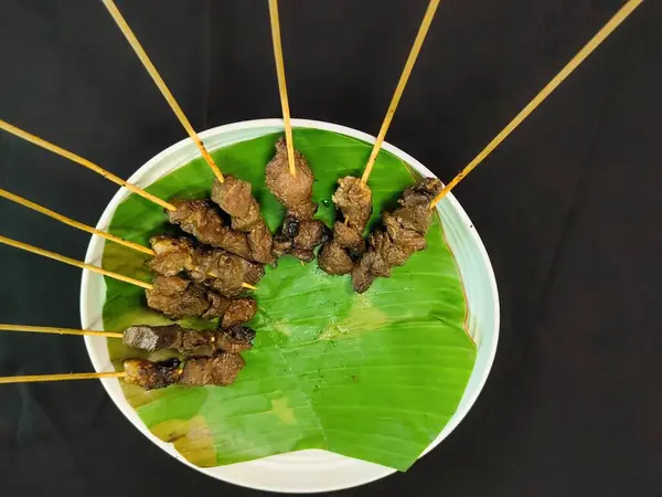 Siyah bir masada bir tabak satay.