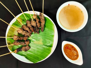 satay dish with complementary seasoning of peanut sauce and soto soup(sate matang)  clipart