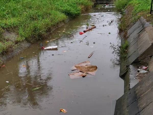 Kirlenmiş küçük bir nehir, yağmur mevsiminde bir sürü çöp taşır.